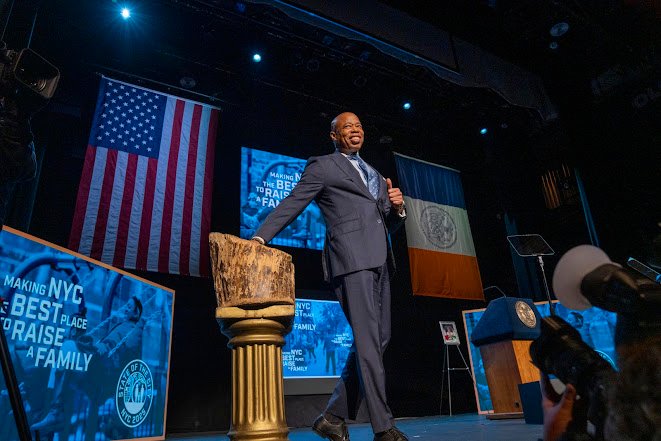 Eric Adams presenta su reelección centrada en vivienda y seguridad en Nueva York Imagen abstracta con tonos oscuros y luces.